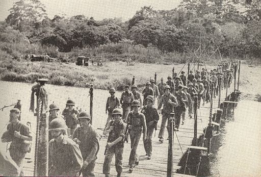 a troop of soldiers crossing a bridge on an island