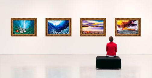 Man sitting looking at four pieces of art on wall