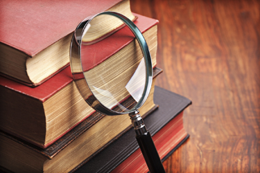 magnifying glass against a stack of old books