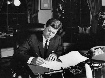 President John F. Kennedy signing documents