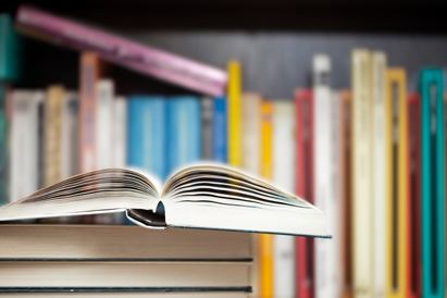 books on a table with more books on a shelf in the background